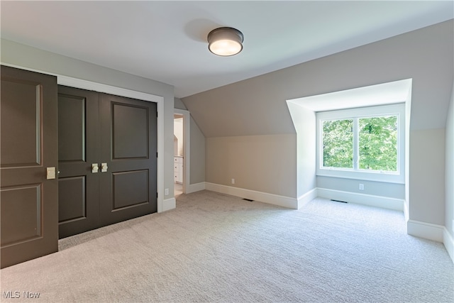 additional living space with light colored carpet and vaulted ceiling