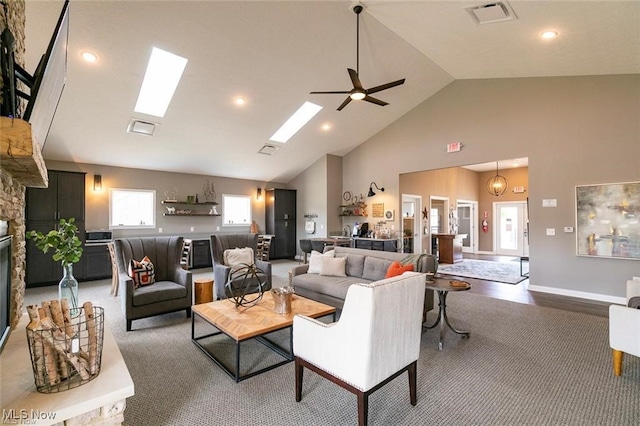 living room with hardwood / wood-style flooring, a fireplace, high vaulted ceiling, a skylight, and ceiling fan