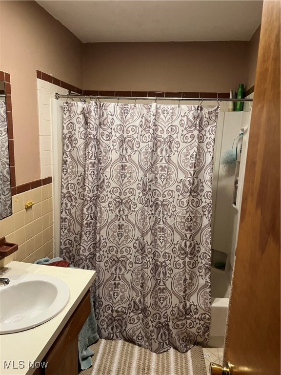 bathroom featuring vanity, shower / tub combo, and tile walls