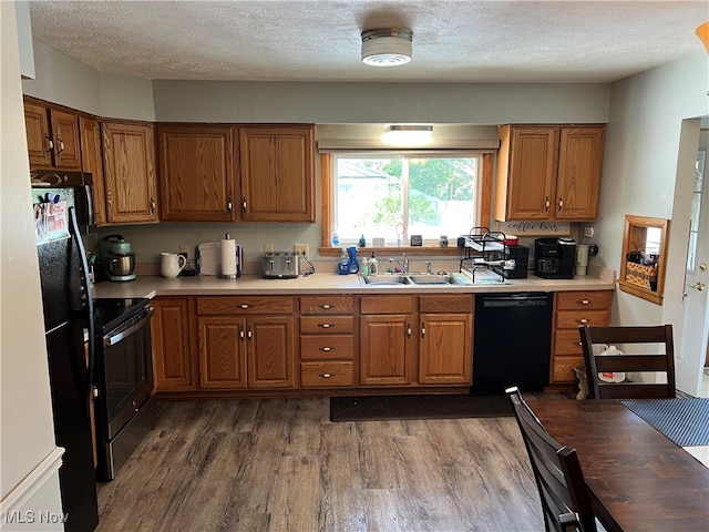 kitchen with black appliances, a textured ceiling, sink, and dark wood-type flooring