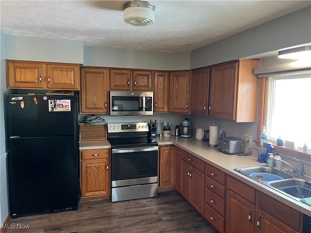 kitchen with a textured ceiling, dark wood-type flooring, sink, and appliances with stainless steel finishes