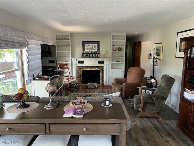 living room with dark wood-type flooring, a fireplace, and a textured ceiling