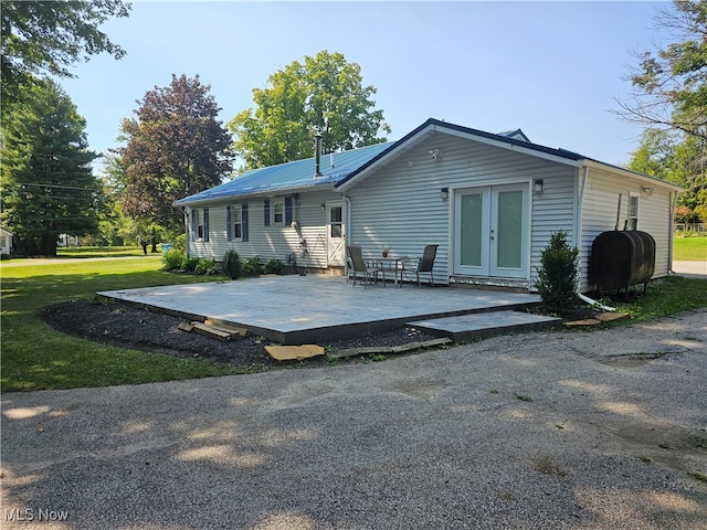 back of property with a patio, a yard, and french doors