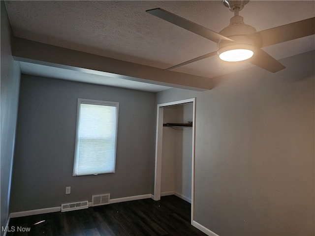 unfurnished bedroom featuring a closet, ceiling fan, dark wood-type flooring, and a textured ceiling