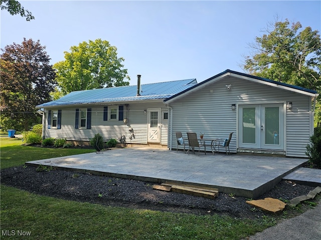 rear view of house featuring french doors, a wooden deck, a yard, and a patio area