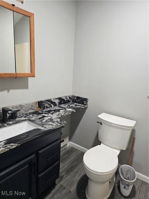 bathroom featuring baseboard heating, hardwood / wood-style floors, vanity, and toilet