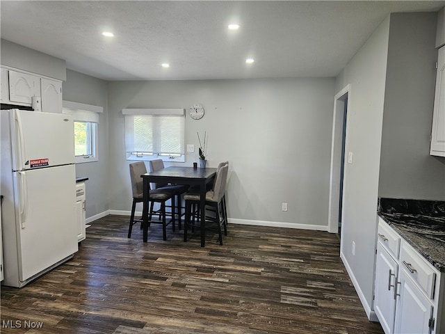 dining area with a textured ceiling and dark hardwood / wood-style flooring