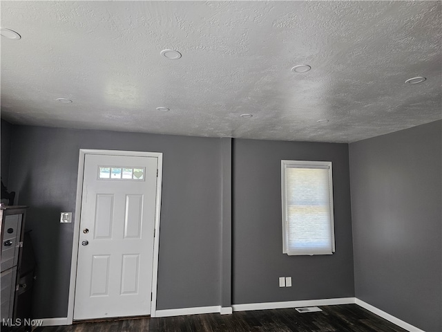 foyer featuring a textured ceiling and dark wood-type flooring