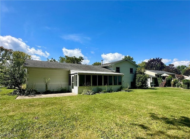 back of property with a sunroom and a lawn