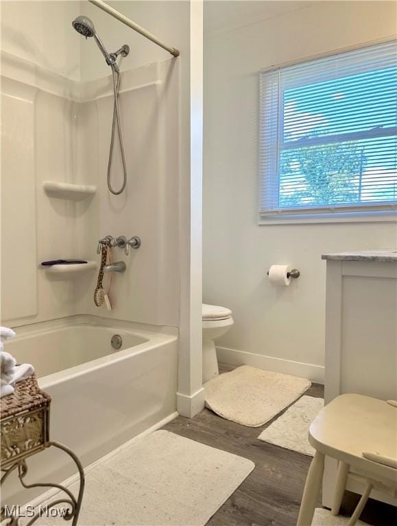 bathroom featuring wood-type flooring,  shower combination, and toilet