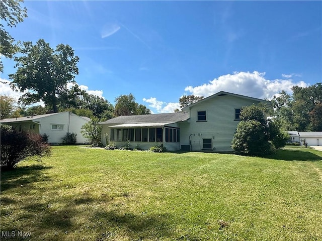 rear view of house featuring a sunroom and a lawn