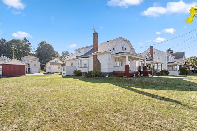 back of house with a lawn, covered porch, and an outdoor structure