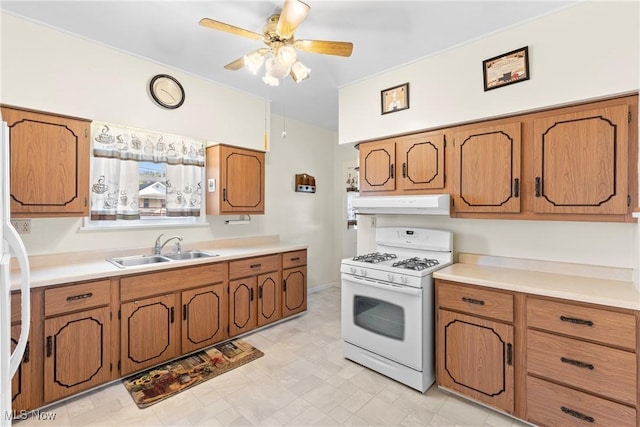 2110 Commerce St, Wellsburg, WV 26070 - kitchen with white gas stove, brown cabinetry, under cabinet range hood, and a sink