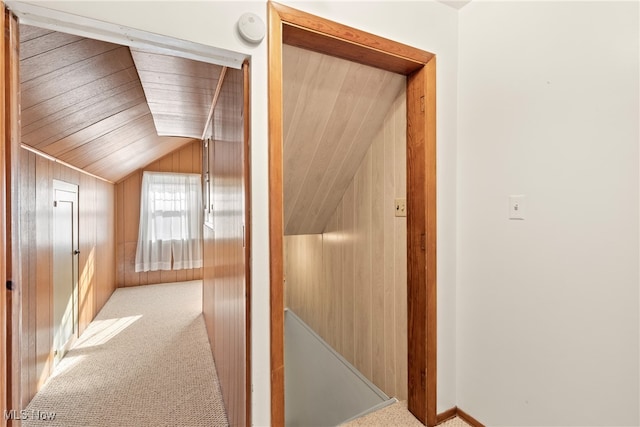 hall with lofted ceiling, wood walls, carpet flooring, and wooden ceiling