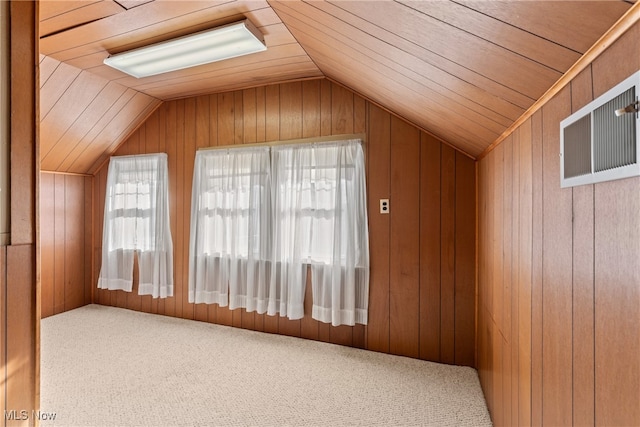 additional living space with lofted ceiling, wood walls, and carpet flooring