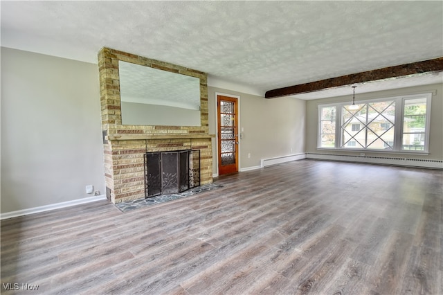 unfurnished living room with a brick fireplace, baseboard heating, beamed ceiling, wood-type flooring, and a textured ceiling