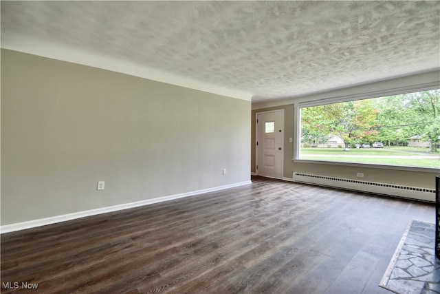 empty room with a textured ceiling, a baseboard radiator, and hardwood / wood-style floors