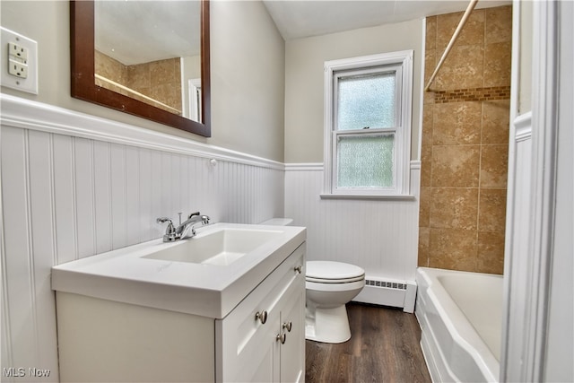 full bathroom featuring toilet, tiled shower / bath, vanity, baseboard heating, and hardwood / wood-style flooring