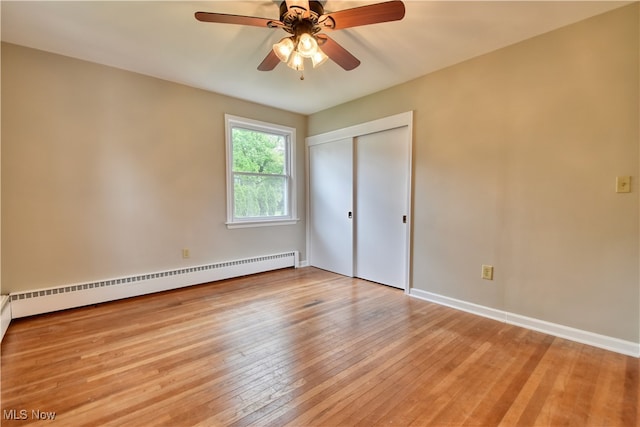 spare room featuring a baseboard heating unit, ceiling fan, and light hardwood / wood-style floors