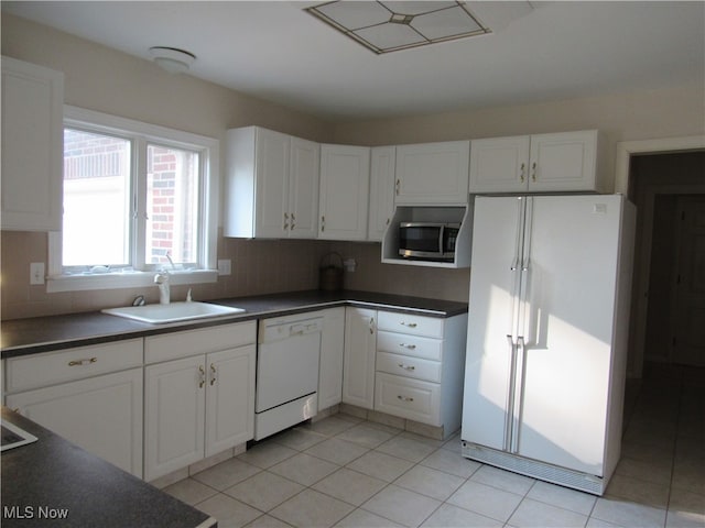 kitchen with sink, light tile patterned floors, white appliances, and white cabinets