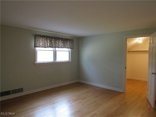 unfurnished bedroom with light hardwood / wood-style floors, a walk in closet, and a closet