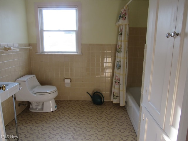 bathroom with tile walls, toilet, and shower / bath combination with curtain