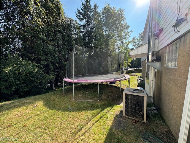 view of yard with a trampoline and central AC