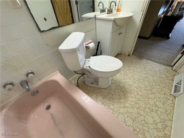 bathroom featuring a tub to relax in, vanity, toilet, and tile walls