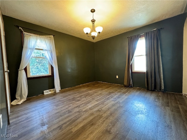 unfurnished room featuring dark wood-type flooring, a notable chandelier, and a textured ceiling