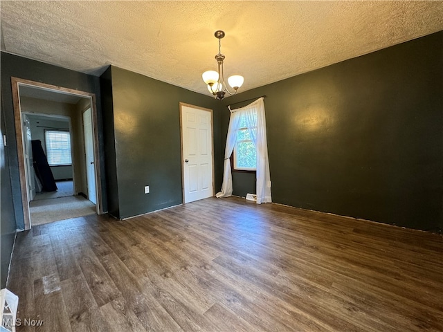 unfurnished room featuring a textured ceiling, dark hardwood / wood-style floors, and a notable chandelier