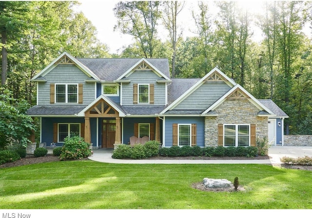 craftsman inspired home with a front lawn, a porch, and a shingled roof