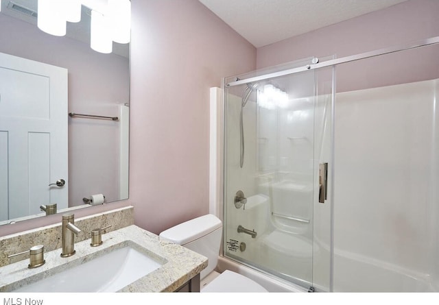 full bathroom with shower / bath combination with glass door, vanity, toilet, and a textured ceiling