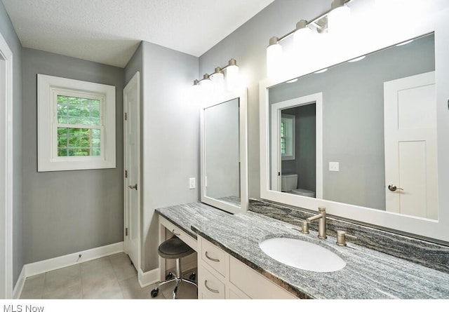 bathroom featuring vanity, toilet, tile patterned floors, and a textured ceiling