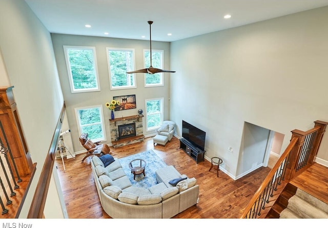 living room with a fireplace, a towering ceiling, and hardwood / wood-style floors