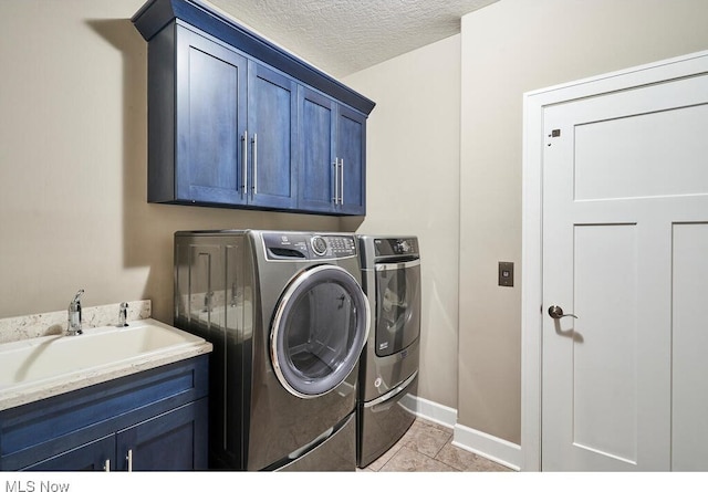 laundry area featuring light tile patterned floors, washing machine and dryer, sink, cabinets, and a textured ceiling