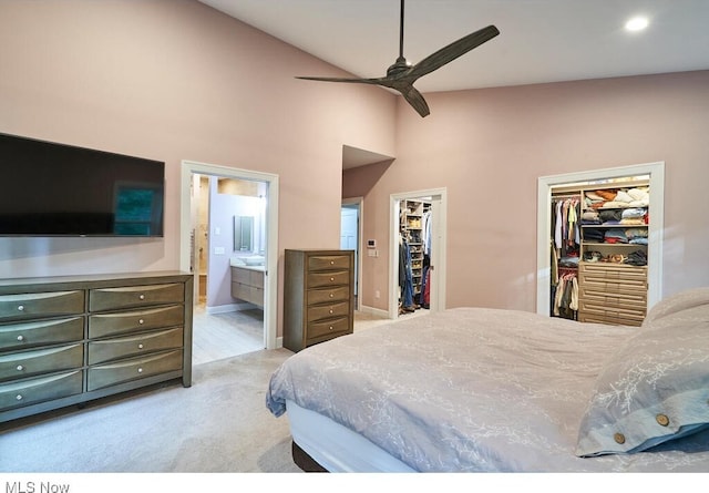 bedroom featuring ceiling fan, a closet, a spacious closet, light colored carpet, and ensuite bathroom