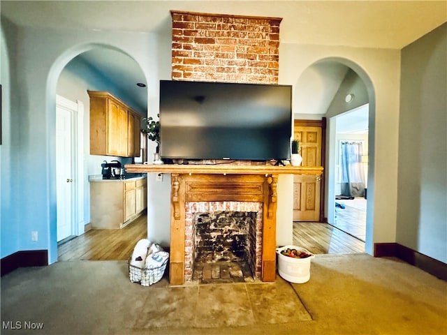 living room with lofted ceiling, a brick fireplace, and light hardwood / wood-style floors