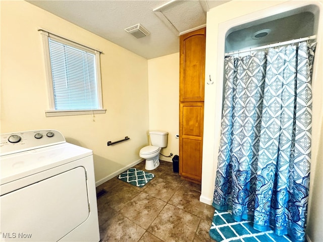 bathroom with washer / dryer, tile patterned flooring, toilet, and a textured ceiling