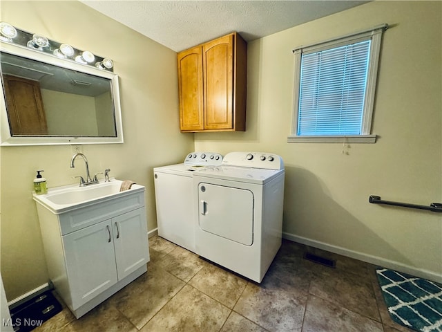 laundry area featuring light tile patterned flooring, cabinets, washing machine and clothes dryer, sink, and a textured ceiling