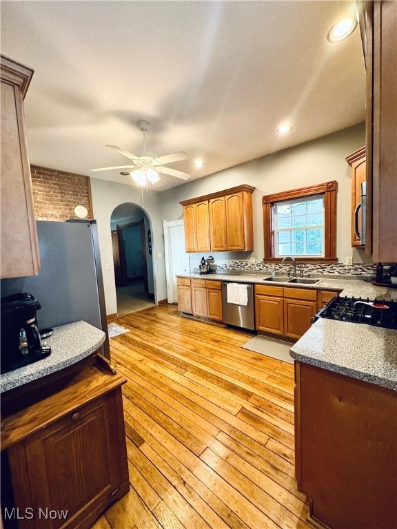 kitchen with light hardwood / wood-style floors, appliances with stainless steel finishes, sink, and ceiling fan