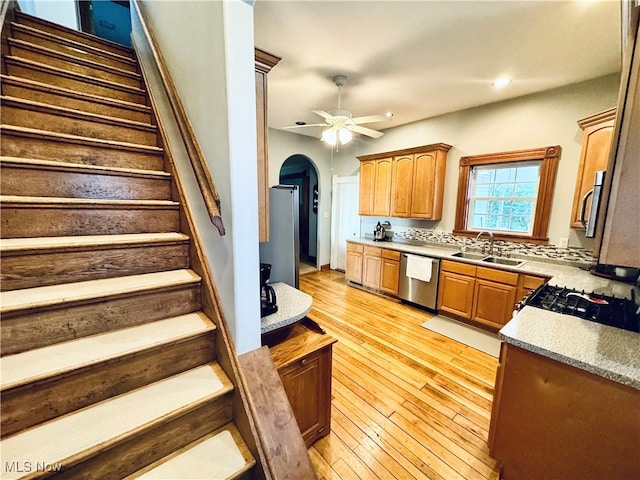 kitchen featuring ceiling fan, light hardwood / wood-style flooring, sink, backsplash, and appliances with stainless steel finishes