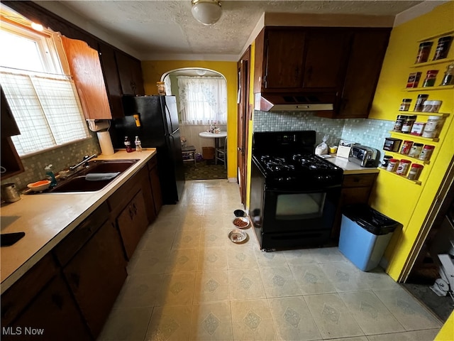 kitchen with tasteful backsplash, a textured ceiling, exhaust hood, sink, and black appliances