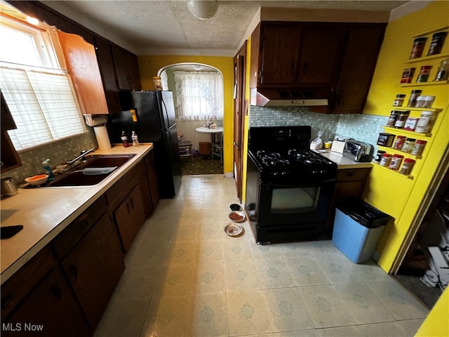 kitchen with sink, ventilation hood, a textured ceiling, decorative backsplash, and black appliances