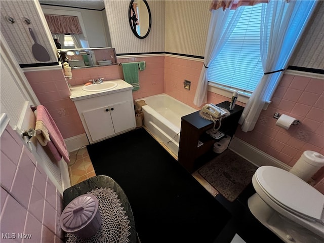 bathroom featuring vanity, a tub to relax in, toilet, and tile walls