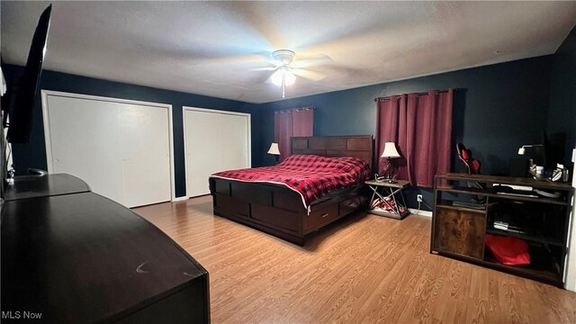 bedroom featuring light wood-type flooring, two closets, ceiling fan, and a textured ceiling