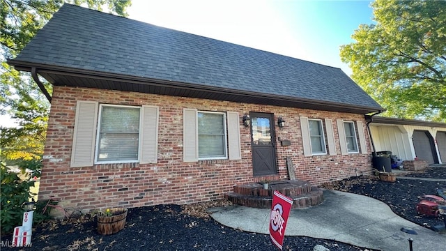 view of front of house with brick siding, roof with shingles, and an attached garage