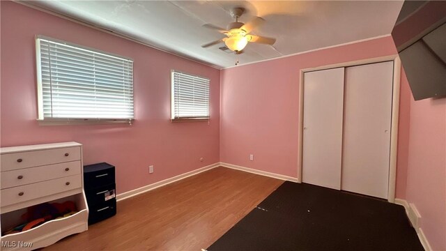 unfurnished bedroom featuring ceiling fan, a closet, light wood-type flooring, and multiple windows