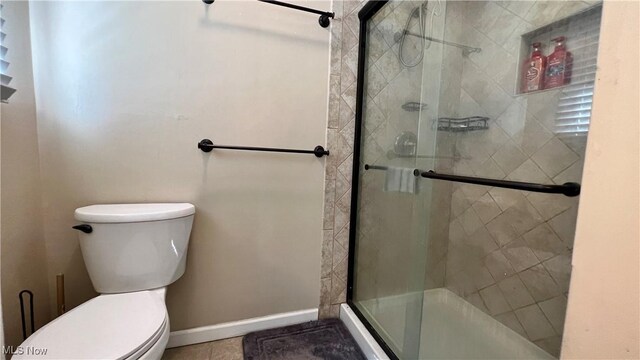 bathroom featuring toilet, walk in shower, and tile patterned floors