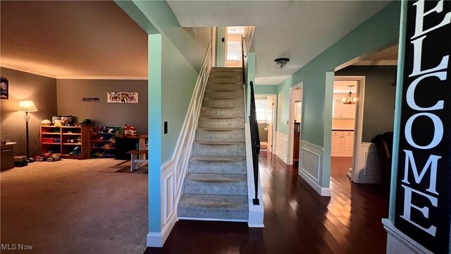 staircase featuring ornamental molding and hardwood / wood-style flooring