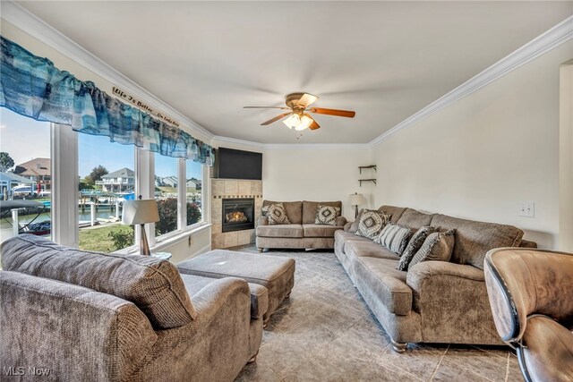 tiled living room with ornamental molding, a tiled fireplace, and ceiling fan